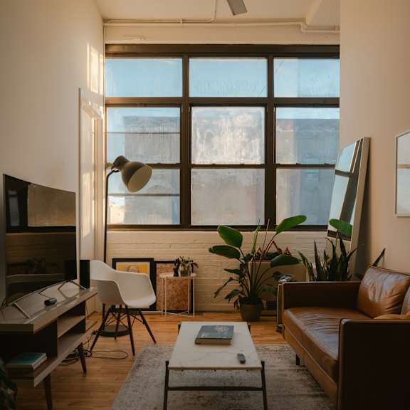 A living room with a brown couch, a white chair, a coffee table, and a ceiling fan.