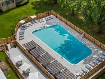 A rectangular pool surrounded by a wooden fence and lounge chairs.