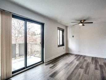 A room with a ceiling fan and sliding glass doors.