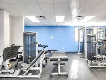 A gym with a variety of equipment including a bench press, a leg press, and a squat rack.
