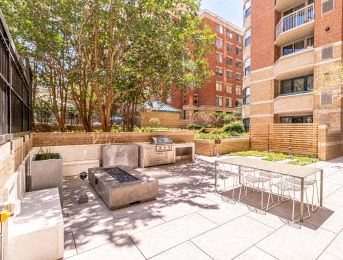 A patio with a table and chairs is surrounded by a brick building.