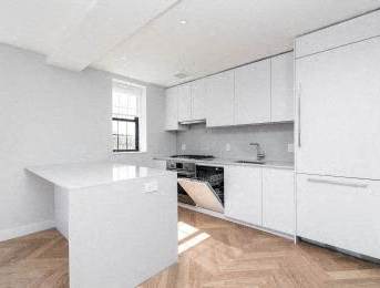 A kitchen with white cabinets and a white island.