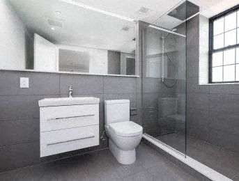 A white toilet sits next to a sink in a modern bathroom.