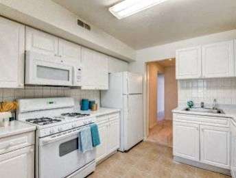 A kitchen with white appliances and cabinets.