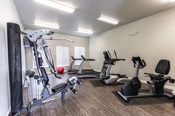 A gym with a variety of equipment including a leg press machine, a treadmill, and a stationary bike.