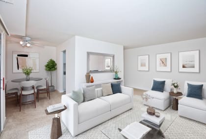 a living room with white walls and a white couch with blue pillows at Fairfax Square, Fairfax, VA