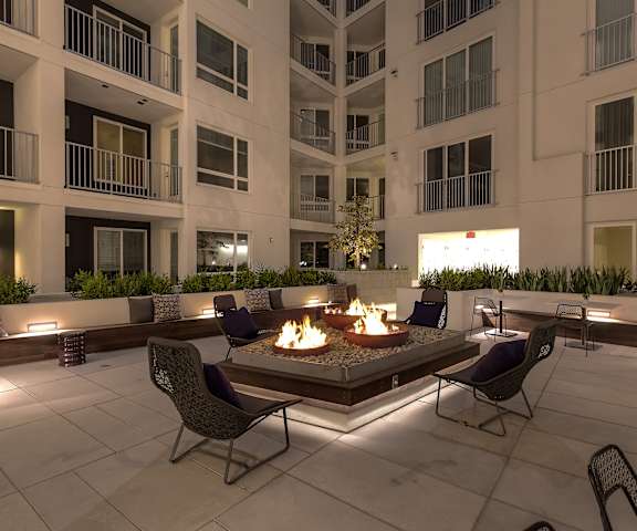 A fire pit sits in the middle of a patio surrounded by chairs.