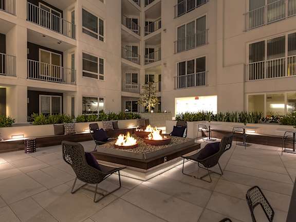 A fire pit sits in the middle of a patio surrounded by chairs.