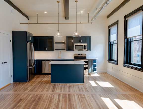 A kitchen with a black refrigerator and a white island.