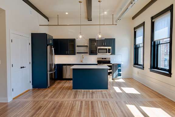 A kitchen with a black refrigerator and a white island.