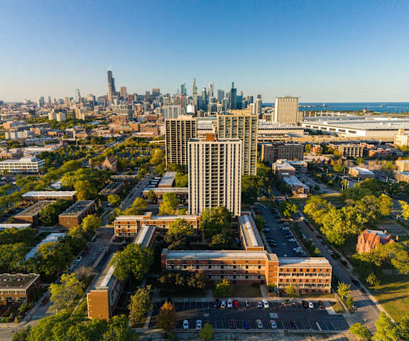 A cityscape with a mix of modern and older buildings, a parking lot, and a clear sky.