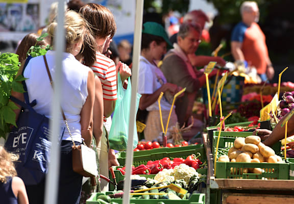 people buying fruits and vegetables at an outdoor market