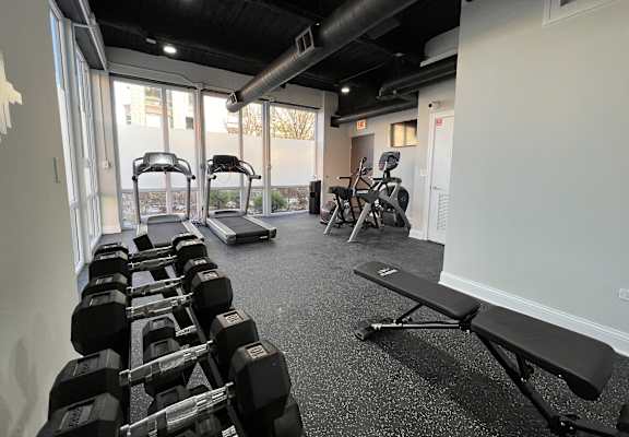 Fitness center at Highpoint Wicker Park in Chicago with cardio machines, free weights, and floor-to-ceiling windows