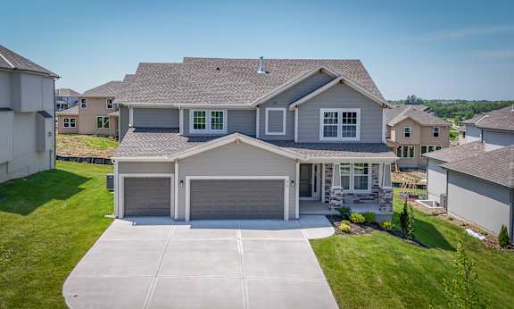 A large house with a garage is surrounded by other houses.