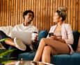 a man and a woman sitting on a couch holding a laptop and a phone