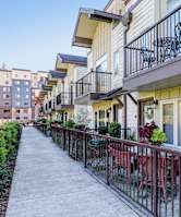A row of apartment buildings with balconies and a walkway in the foreground.