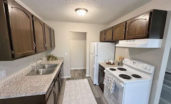 A kitchen with a white stove top oven and a white refrigerator.