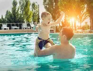 A man is holding a child in a swimming pool.