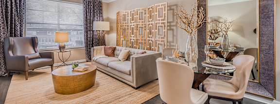 A modern living room with a wooden floor and a large mirror on the wall. at The Spring at Silverton Apartments, Texas, 76133