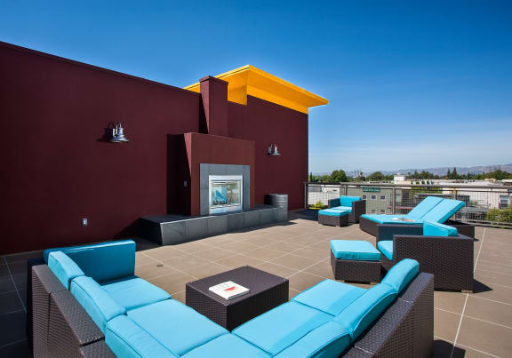a lounge area on the roof of a building with blue couches and chairs at Legacy Apartments, Northridge, Califiornia