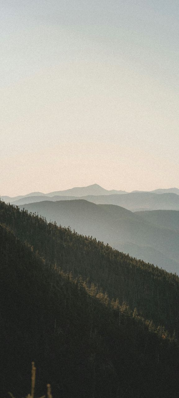 A mountain range covered in greenery with a hazy sky.