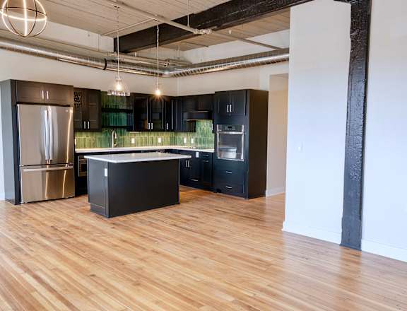 A kitchen with a refrigerator, oven, and sink.