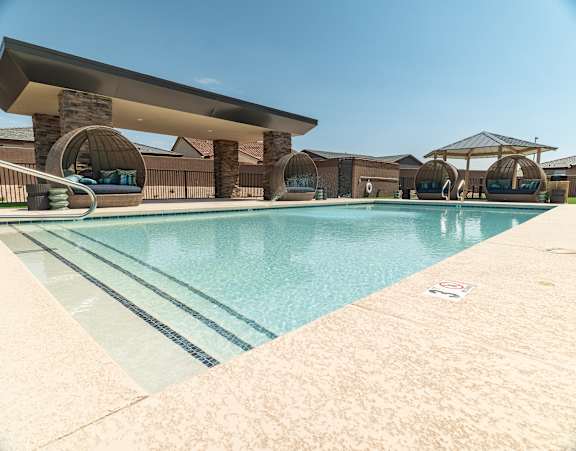 A large outdoor swimming pool with a sun lounger and a shade structure.
