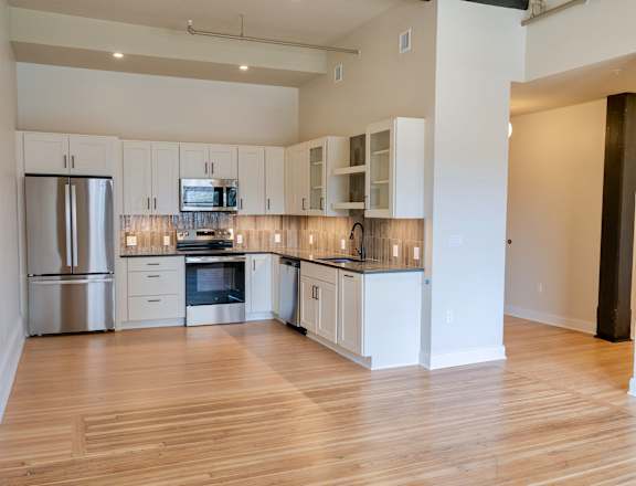 A kitchen with white cabinets and wooden floors.