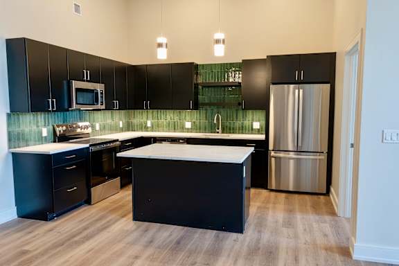 A kitchen with black cabinets and a white island.