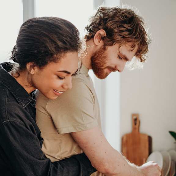 A man and a woman are cooking together in a kitchen.