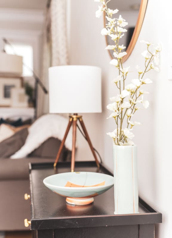 Lamp on end table with small plant and trinkets