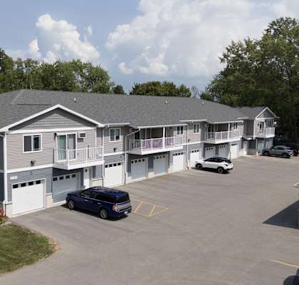 a view of an apartment building with cars parked in a parking lot
