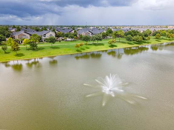 A fountain in the middle of a lake in a residential area at Avenues at Shadow Creek Ranch Apartments, Pearland, Texas