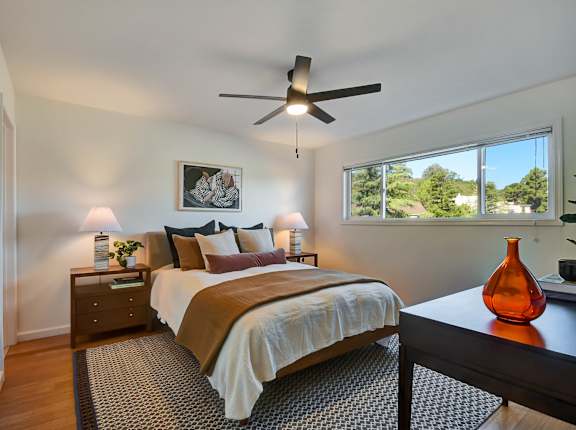 A bedroom with a bed, nightstand, and a ceiling fan.
