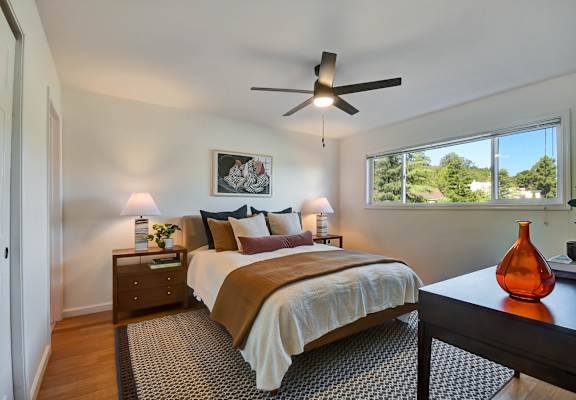 A bedroom with a bed, nightstand, and a ceiling fan.