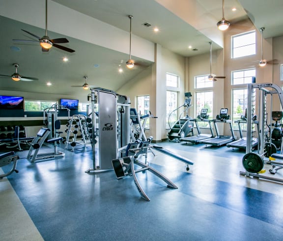 a large fitness room with cardio machines and other exercise equipment