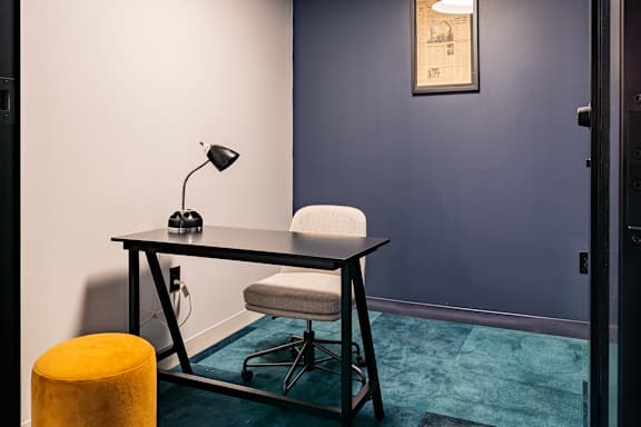 A room with a desk, chair, and lamp.