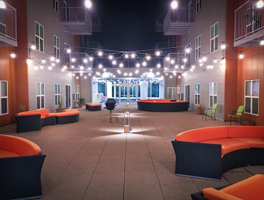 an open area with orange couches and chairs and string lights