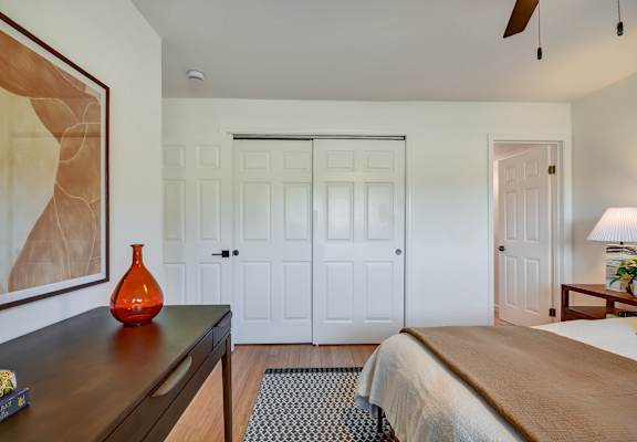 A bedroom with a bed, a dresser, and a painting on the wall.
