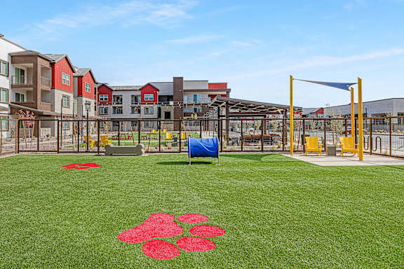 A playground with a blue tarp and red flower pattern on the grass.