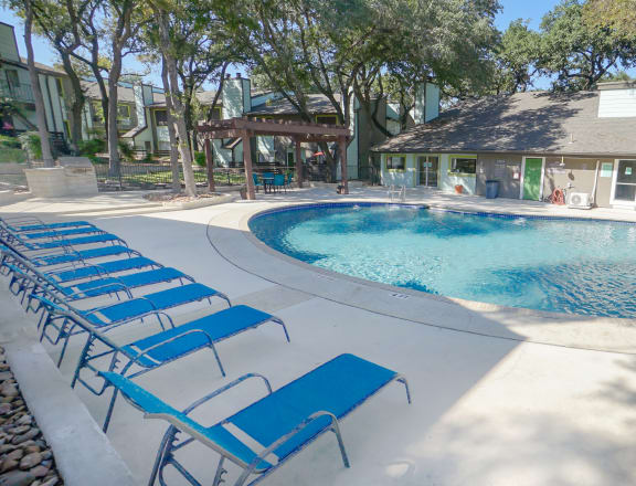 a pool with blue chaise lounge chairs and umbrellas