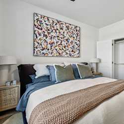 A bedroom with a large bed and a painting on the wall.