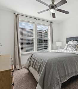 A bedroom with a bed, nightstand, and a ceiling fan.