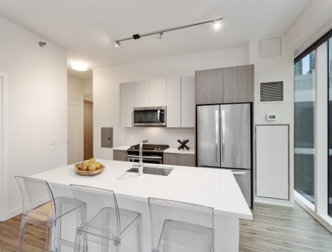 a kitchen with a white counter top and a stainless steel refrigerator