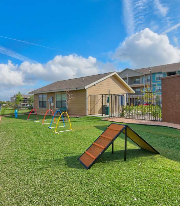 A playground with a slide and a tree in a grassy area.
