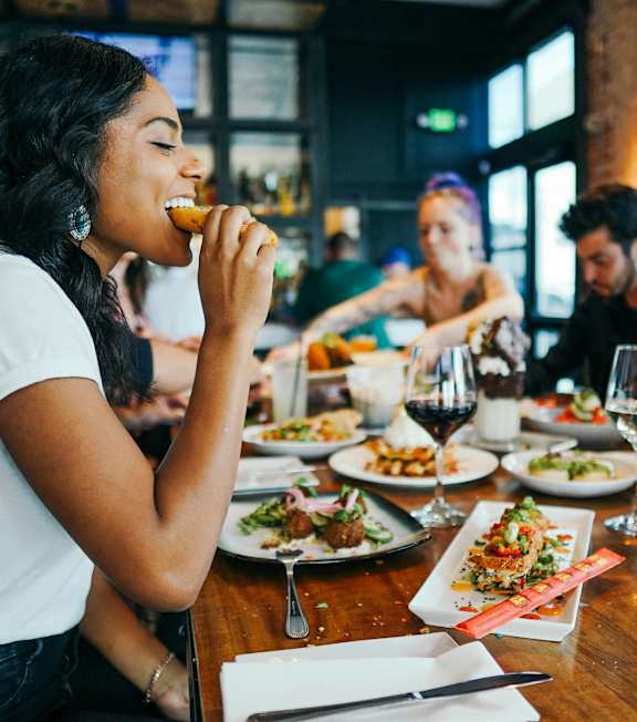 A woman is eating in a restaurant with a group of people.