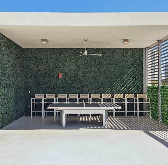 1- & 2-Bedroom Apartments for Rent in Miami, FL – Riverview One Apartments – A patio with a ping pong table and chairs under a white roof.