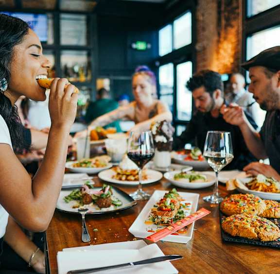 A woman is eating in a restaurant with a group of people.