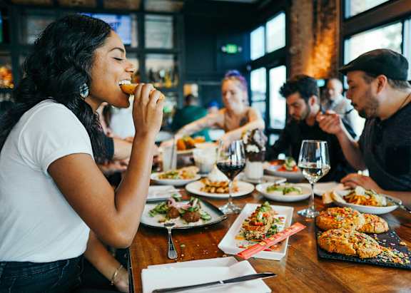 A woman is eating in a restaurant with a group of people.