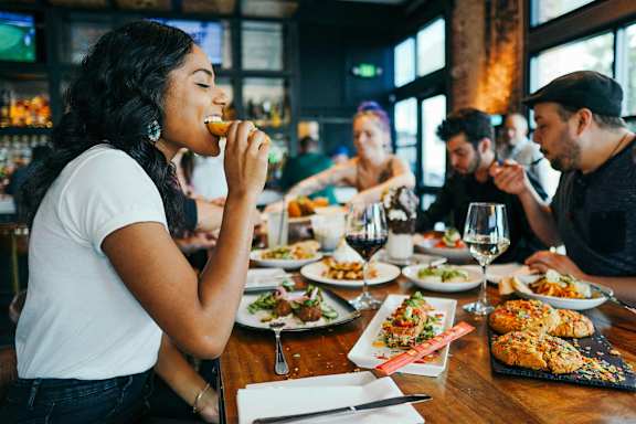 a group of people sitting at a table eating food at a restaurant